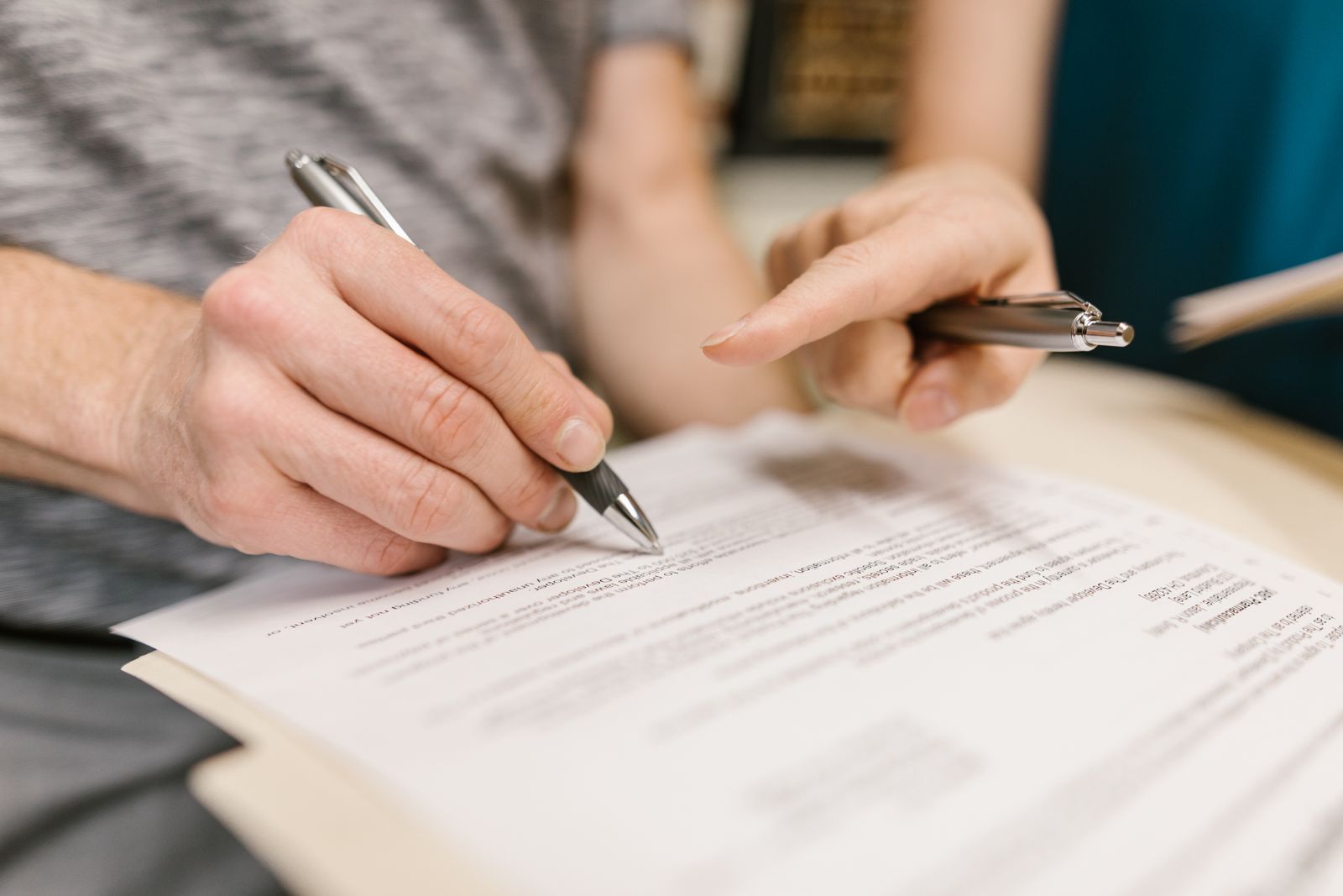 Two people reviewing paperwork with pens