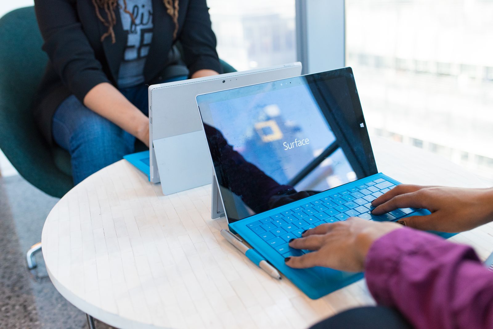 Hands using a Microsoft Surface computer at a work desk